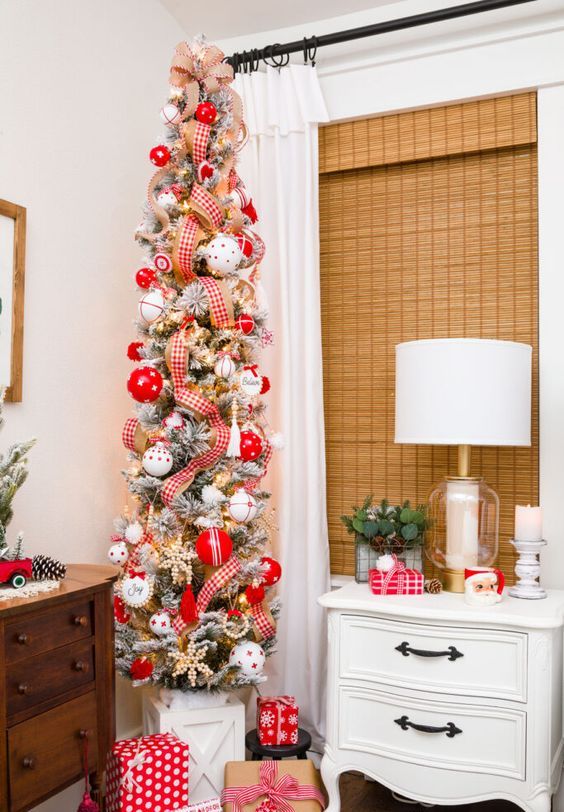 a bright skinny flocked Christmas tree with plaid ribbons, red and white ornaments and bead snowflakes is a catchy decoration