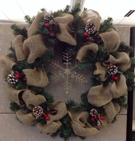 a burlap and evergreen wreath with a rhinestone snowflake, snowy pinecones and cranberries