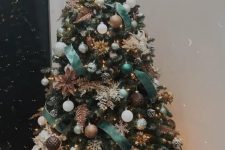 a catchy Christmas tree with green ribbons, white snowflakes and faux blooms, white and brown ornaments, pinecones and lights