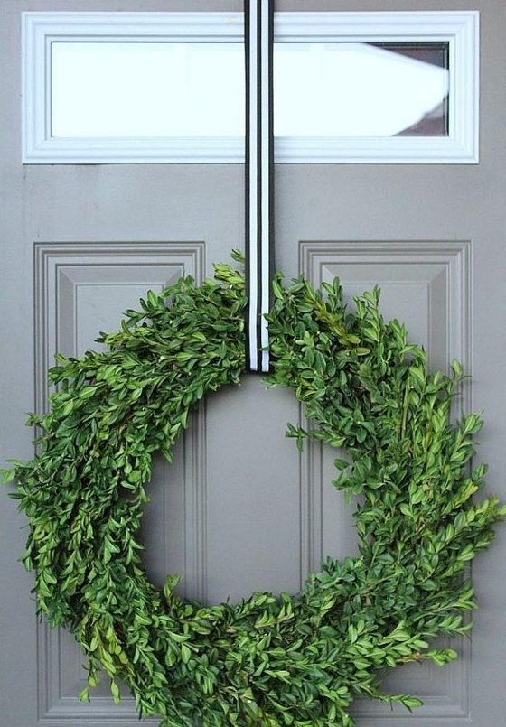 a catchy Christmas wreath of boxwood, with a striped ribbon will match many styles and decor themes