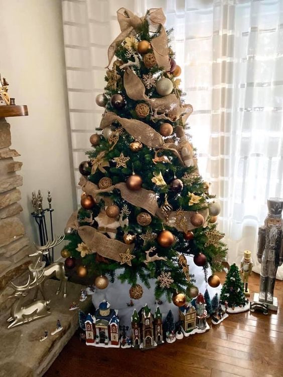 a catchy rustic Christmas tree with copper, gold and brown ornaments, burlap ribbons and lights plus dollhouses under the tree