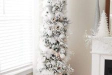 a charming flocked skinny Christmas tree with fluffy garlands, white ornaments and snowflakes plus a star topper