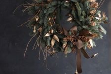 a chic and elegant rustic Christmas wreath of evergreens, brown leaves, twigs and a bow