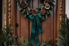 a classic rustic Christmas wreath of evergreens, pinecones and a green bow is amazing