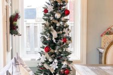 a classic slim Christmas tree styled with ribbons, silver and red ornaments, snowflakes and bells is lovely