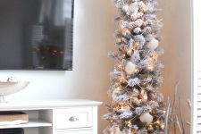 a classy flocked pencil Christmas tree decorated with beads, snowy pinecones, seashells, starfish and lights