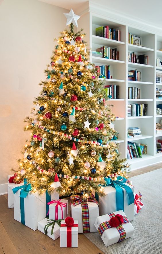 a colorful Christmas tree styled with bold ornaments, lights and bright pompoms is amazing