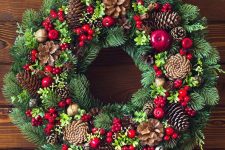 a colorful rustic Christmas wreath of evergreens, berries, blooms, pinecones and other stuff