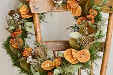a cool modern rustic Christmas wreath with greenery, berries, citrus slices and foliage is a bold and cool decoration