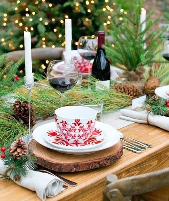 a cozy Christmas tea party tablescape with tree slice placemats, printed porcelain, evergreens, pinecones and candles