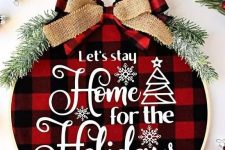 a cozy Christmas wreath with red plaid fabric, white letters, evergreens and a couple of bows on top is amazing
