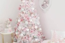 a cute white Christmas tree styled with pastel pink, green and white ornaments, pink hearts, snowflakes, stars and a bow on top