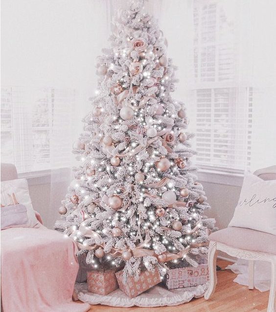 A delicate and refined glam Christmas tree with white and pink ornaments, with lights, flowers and ribbons is just jaw dropping