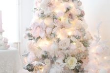 a delicate flocked Christmas tree decorated with whte and blush faux blooms, bows and lights is amazing