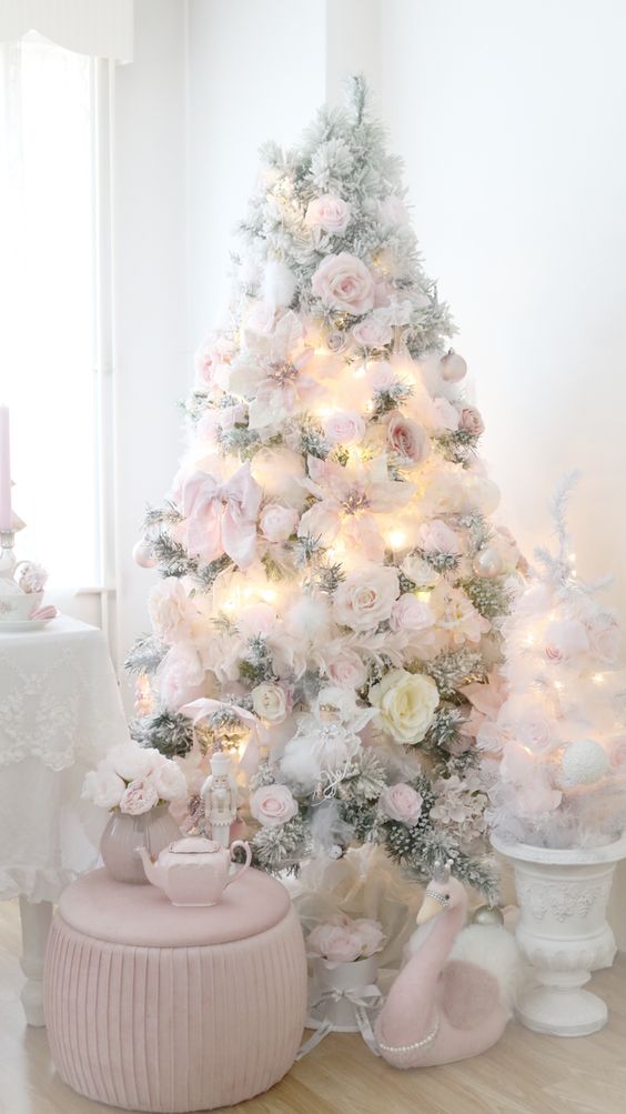 a delicate flocked Christmas tree decorated with whte and blush faux blooms, bows and lights is amazing