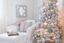 a delicate flocked Christmas tree with blush, light green and silver ornamnets and branches is a chic and cool idea