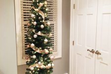 a delicate pencil Christmas tree decorated with ribbon and neutral ornaments plus branches on top is a stylish idea