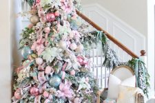 a fantastic pastel Christmas tree decorated with pastel pink and blue ornaments, ribbons, greenery branches and a creative topper