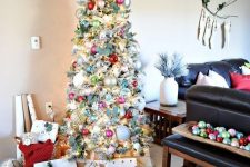 a flocked Christmas tree decorated vintage style with silver, pink, red and light green ornaments, fresh greenery and lights looks magical