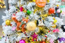 a flocked Christmas tree decorated with all kinds of colorful ornaments, beads, stars and toys is amazing