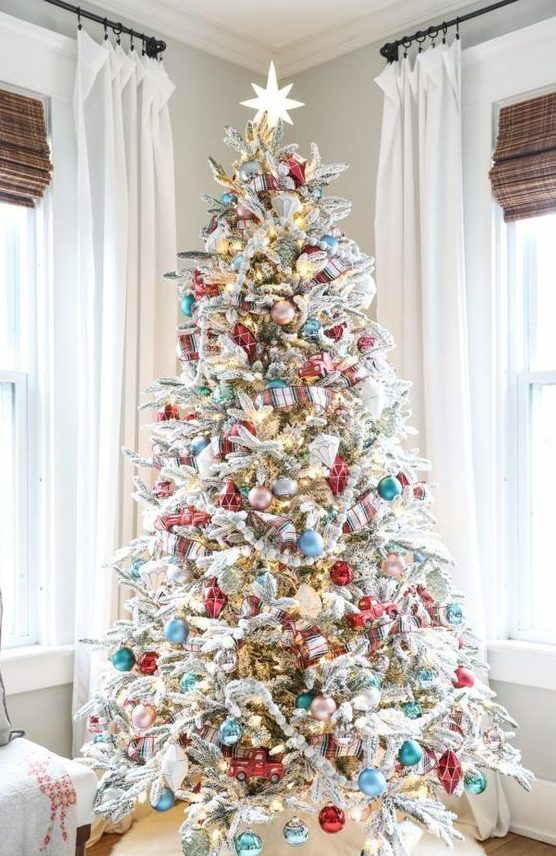a flocked Christmas tree decorated with blue, pink, turquoise and metallic ornaments and lights plus plaid ribbons