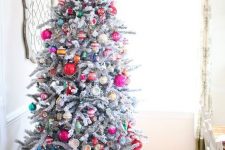 a flocked Christmas tree decorated with colorful vintage ornaments and topped with a star is wow