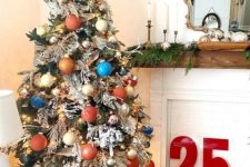 a flocked Christmas tree decorated with creamy, copper, rust, blue and gold ornaments, branches and twigs, greenery and a star topper