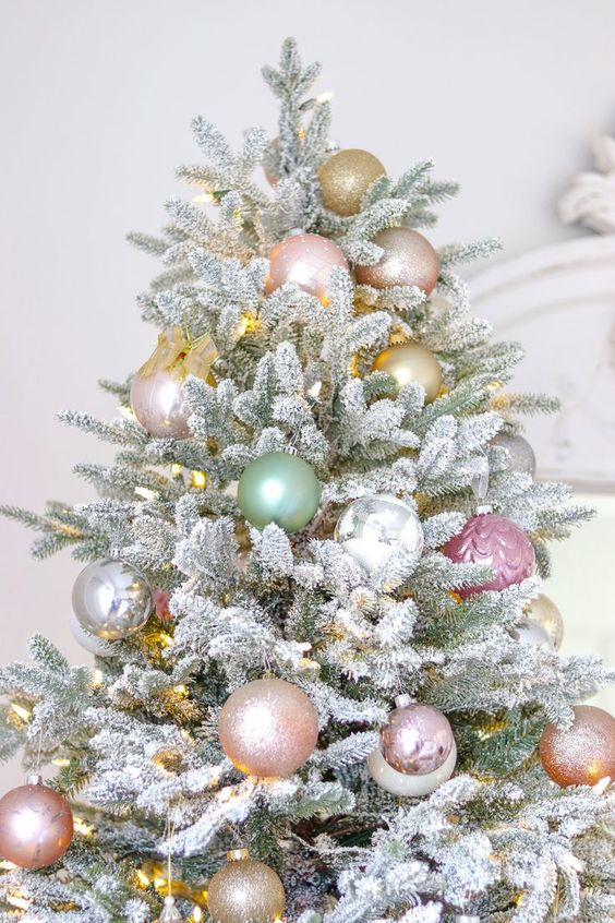 a flocked Christmas tree decorated with pastel green and pink and gold ornaments and lights is a chic and stylish idea