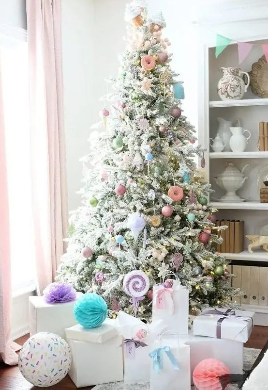 a flocked Christmas tree decorated with pastel ornaments, candy and donut shaped ones, with lights