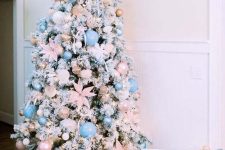 a flocked Christmas tree decorated with pastel pink and blush ornaments, pink fabric flowers and lights is gorgeous