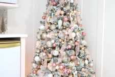 a flocked Christmas tree done with ribbon, pink, blush, white and gold ornaments, a pink star on top and some lights