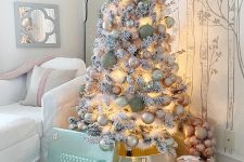 a flocked Christmas tree styled with blush, silver and green ornaments, lights and oversized bells looks wow