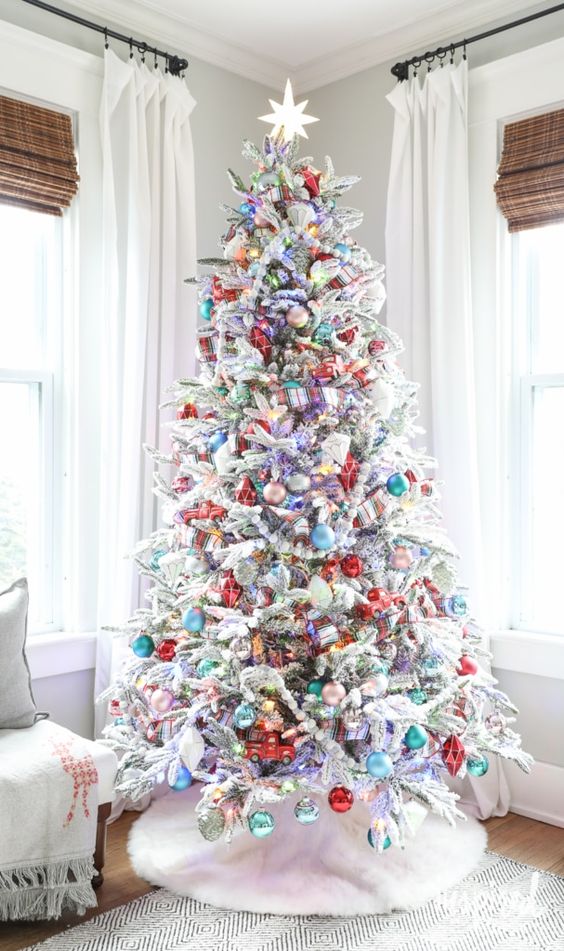 a flocked Christmas tree styled with bold ornaments and lights is a cool and catchy solution for a holiday space