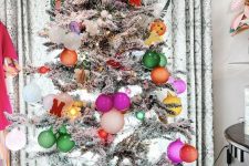 a flocked Christmas tree with bold ornaments and lights is a cool and chic decoration you’ll like