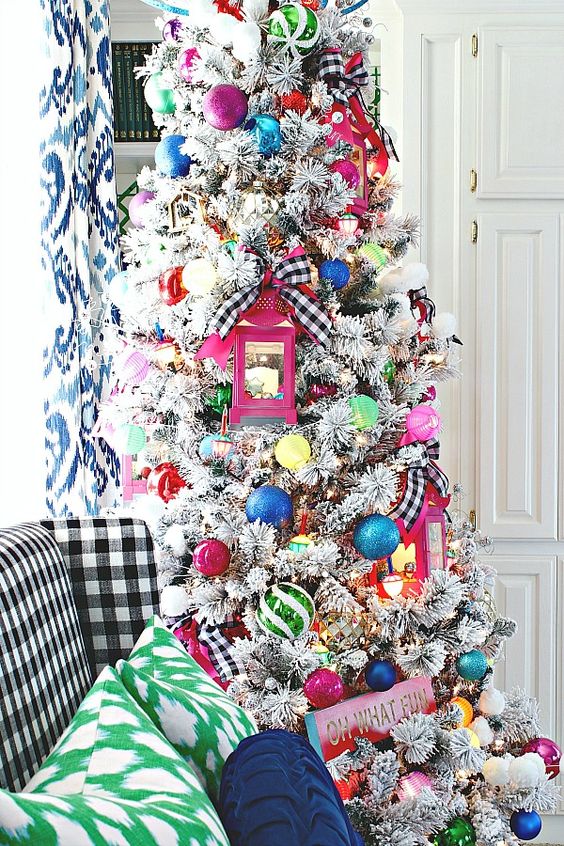a flocked Christmas tree with colorful ornaments, pink lanterns and signs is a fun and cool decoration for the holidays