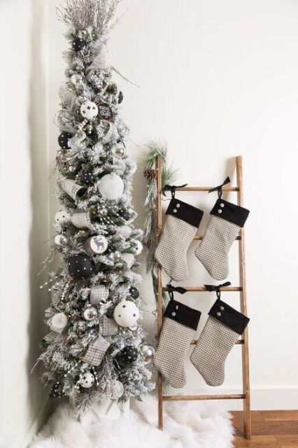 a flocked pencil Christmas tree with black and white ornaments, beads and ribbons plus branches on top
