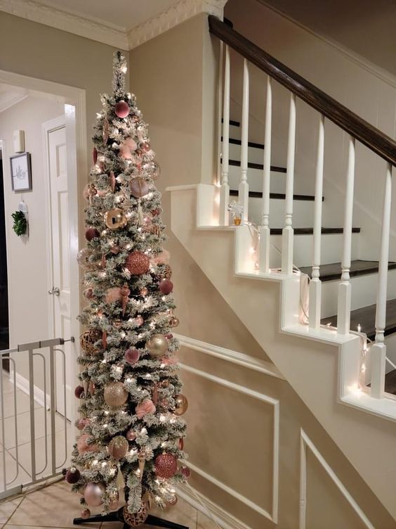 a flocked pencil Christmas tree with lights, gold and pink ornaments looks delicate and subtle