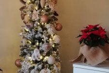a flocked skinny Christmas tree with lights, neutral ornaments and pinecones is a catchy idea