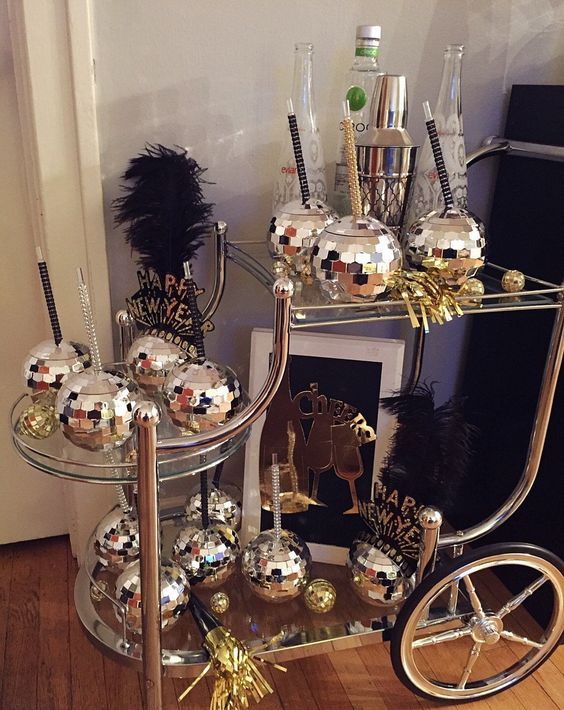a funny NYE bar cart with disco ball glasses for drinks and some alcohol is a super fun and catchy idea