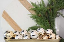 a glam Christmas centerpiece of a gold bowl with gold ornaments is a cool arrangement for the holidays