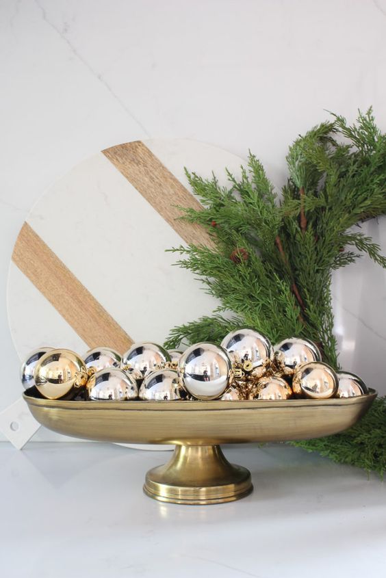 a glam Christmas centerpiece of a gold bowl with gold ornaments is a cool arrangement for the holidays