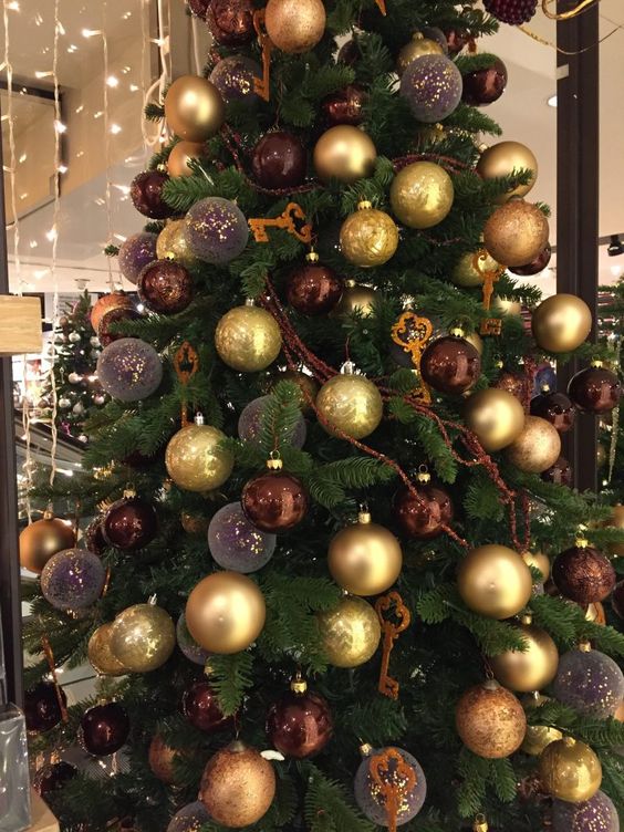 a glam Christmas tree decorated with brown, gold and mauve ornaments, keys and garlands is a cool decoration