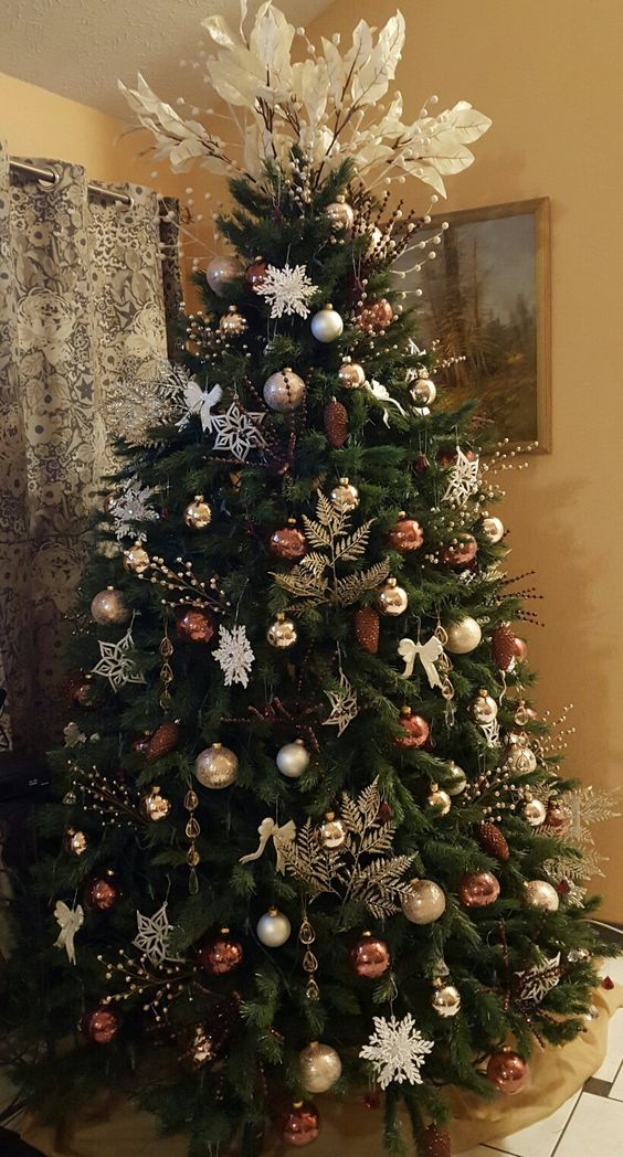 a glam Christmas tree styled with gold leaves, white snowflakes, silver, gold and brown ornaments and white leaves on top