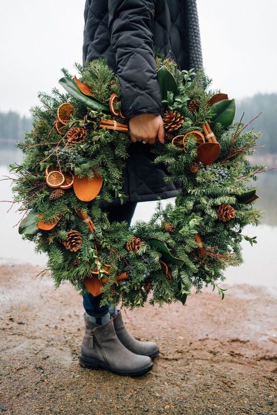 a gorgeous natural meets rustic Christmas wreath of evergreens, pinecones, twigs, citrus slices and magnolia leaves
