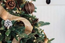 a gorgeous rustic and woodland glam Christmas tree with usual and snowy pinecone ornaments, fabric balls, lights, brown and gold glitter ribbons is wow