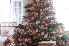 a large Christmas tree decorated with vintage Christmas ornaments and lights and a pink velvet tree skirt