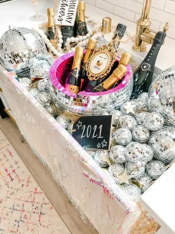 a large sink filled with disco balls and with champagne bottles placed here looks super glam, fun and bold, perfect for a NYE party