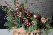 a lovely Christmas decoration of a paper bag with evergreens, berries, acorns, cinnamon and brown ornaments