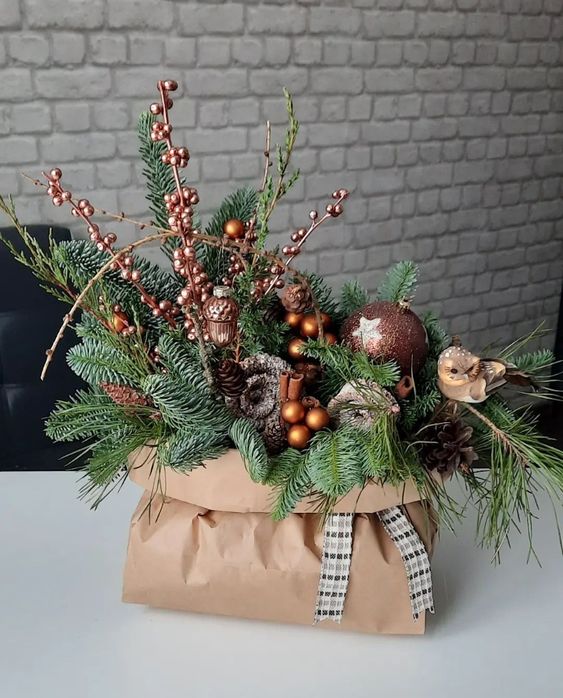 a lovely Christmas decoration of a paper bag with evergreens, berries, acorns, cinnamon and brown ornaments