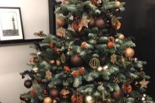 a lovely and glam Christmas tree with brown, copper ornaments, stars and pinecones is amazing